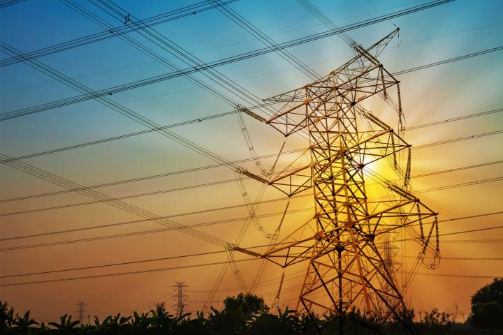 An image showing a transmission tower backlit by the sun.