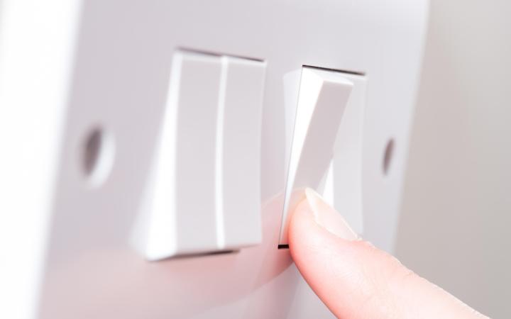Image of a finger pressing a light switch on a wall