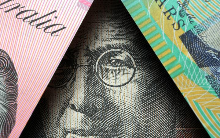 A close-up image of Australian five- and ten-dollar notes obscuring the face of a man featured on another Australian note.
