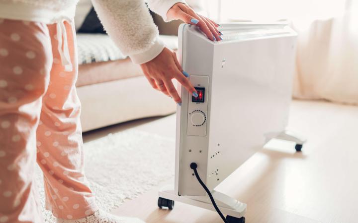 Woman adjusting temperature on portable heater