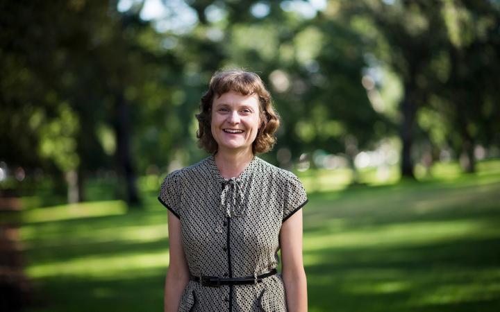 An image of Jodie, strategic communication team member, in a park smiling at something off-camera.